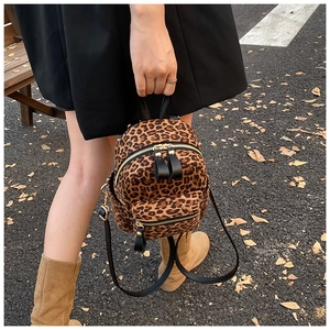Detail of leopard print mini backpack with metal zippers and black leather straps