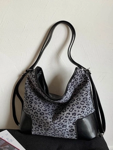 Large leopard print tote bag with black leather straps on a minimalist background