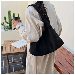 Detail of black suede hobo bag with laser-cut floral patterns shown in lifestyle setting