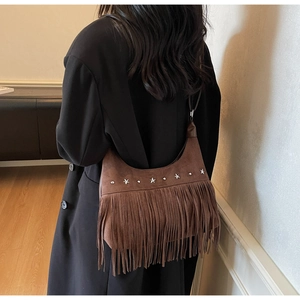 Dettaglio di una borsa hobo in pelle scamosciata marrone con frange lunghe e borchie