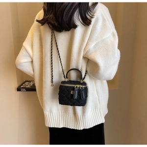 Detail of black faux shearling mini crossbody bag with gold chain strap and floral pendant