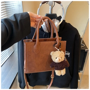 Detailed macro of brown vintage tote bag with HOCOMU embossed logo and cute bear charm