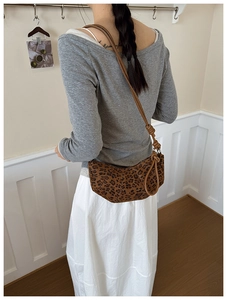 Detail view of leopard print hobo bag with leather strap on a model shoulder