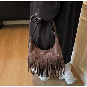Dettaglio della borsa in pelle scamosciata marrone con stelle, borchie e frange lunghe