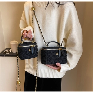 Detail of black tweed crossbody boxes with gold flower charms and chain straps
