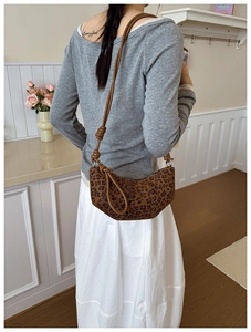 Brown leopard print half-moon bag with elegant knotted strap detail on female model