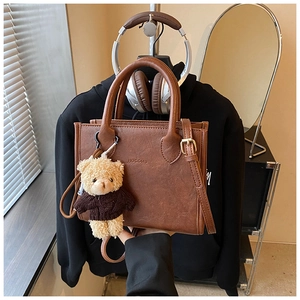 Detailed shot of brown leather tote bag with gold hardware and cute bear keychain