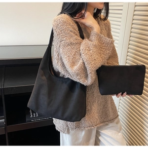 Detail of black matte suede hobo bag with matching zipper pouch on model's shoulder