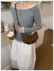 Detail of leopard print crossbody bag with knotted strap shown on model in modern home