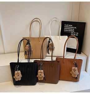 Detail of woven texture tote bags in five colors with cute bear charms on a display stand