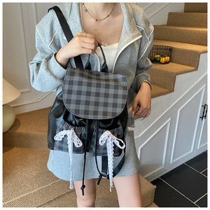 Detail of plaid patchwork backpack with white lace bow and black drawstring closure