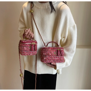 Detail of pink tweed box bag featuring gold floral logo and adjustable chain strap