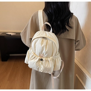 Close-up of minimalist off-white nylon backpack with drawstring pocket and wide straps