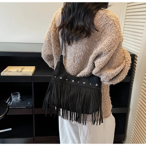 Dettaglio borsa con frange in camoscio nero con borchie a stella sulla spalla della modella