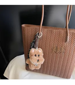 Brown plush poodle bag charm with pearl necklace and TOP DOG tag on a woven tote bag