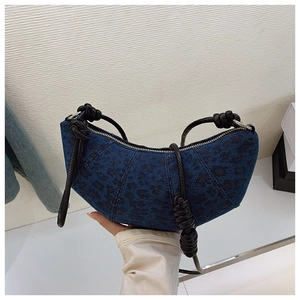 Detail of blue denim leopard print crescent bag featuring black leather knotted strap