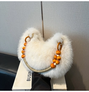 Détail d'un sac à main en fausse fourrure blanche avec perles en bois orange et anneaux dorés