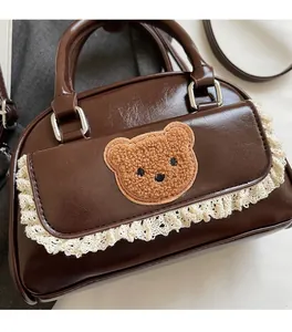 Detail of vintage brown mini crossbody bag with fuzzy bear patch and lace trim detail