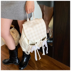 Close-up of beige plaid backpack with lace bow decoration and drawstring closure