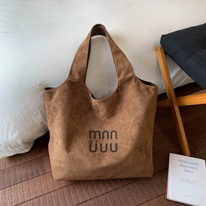 Close-up of brown suede tote bag featuring mnn uuu logo and soft texture finish