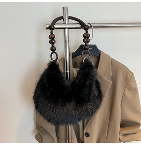 Sac à main en peluche noire avec poignée en perles de bois foncé suspendu au cintre