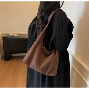 Detailed view of large brown suede hobo bag worn by model in a minimalist modern setting