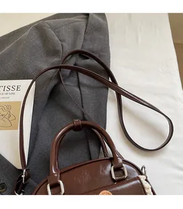 Detail of a dark brown vintage leather handbag with circular handle and silver hardware