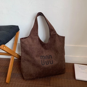 Detailed view of the dark brown suede tote bag with artistic logo on minimalist background
