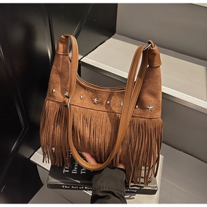 Dettaglio borsa scamosciata marrone con nappe, borchie a stella argento e stile boho