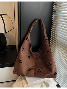Brown faux suede hobo bag with floral cutouts shown in soft window light
