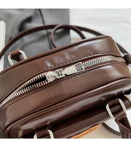 Close-up of smooth silver metal zipper and hardware on deep brown leather shoulder bag