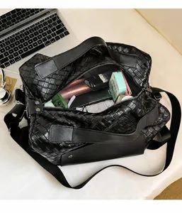Vista dettagliata della borsa da viaggio nera intrecciata con interno capiente e tracolla