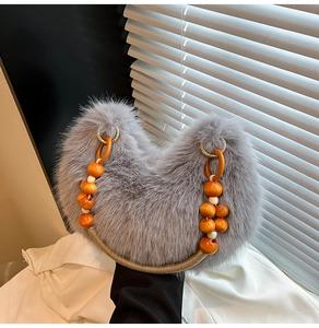 Détail d'un sac en peluche gris avec des perles orange en bois et une anse tressée