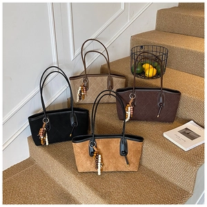 Detailed view of quilted suede tote bags in four autumn colors with beaded charms
