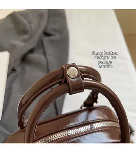 Detail of dark brown leather handbag handles with silver snap button and zipper teeth