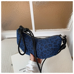 Detail of leopard print denim crescent bag with black knotted rope shoulder strap