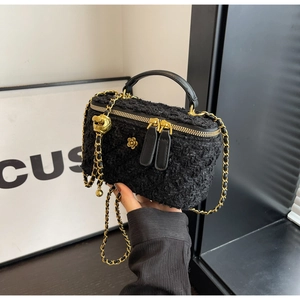 Detail of tweed vanity case with gold ball chain and camellia charm in black finish