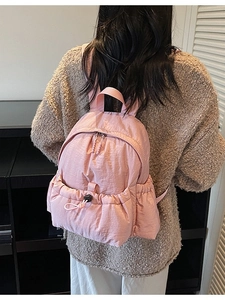 Light pink canvas backpack with drawstring front pocket and adjustable straps for women