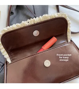 Detail view of brown leather bag with lace trim, front pocket, and magnetic snap closure