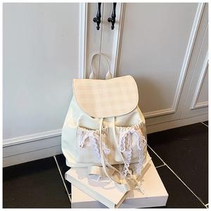 Detail of cream backpack featuring beige checkered flap and white lace bow pockets