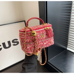 Close-up of pink tweed handbag featuring a gold flower accent and chain strap detail