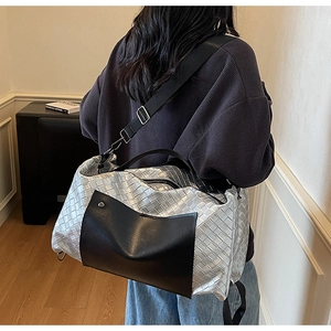 Foto indossata di una grande borsa da viaggio intrecciata argento con tasche nere
