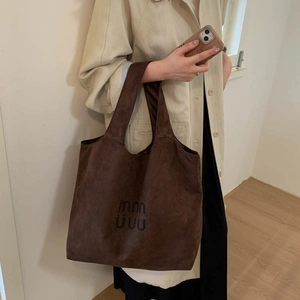 Detailed view of the dark brown suede tote bag featuring a minimalist printed logo