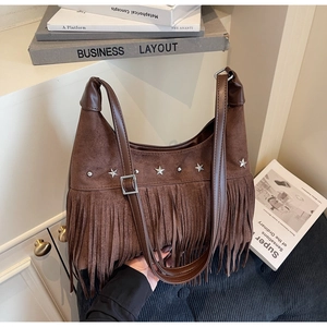 Dettaglio della borsa in pelle scamosciata marrone con borchie a stella e frange boho