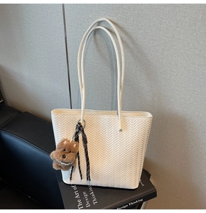 Detail of white woven tote bag with a cute brown puppy plush charm on a book