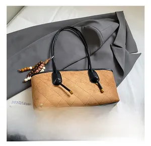 Detail of vintage brown suede tote bag featuring diamond quilting and wooden bead charm