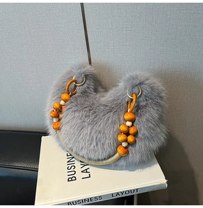 Gros plan du sac en fausse fourrure grise avec anse en perles de bois et anneau doré
