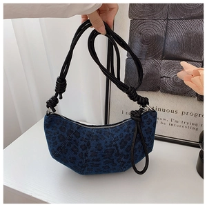 Close-up of blue denim leopard print crescent bag with black knotted rope shoulder strap