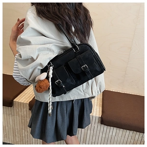Detail of vintage black workwear shoulder bag with dual pockets and plush charm accessory