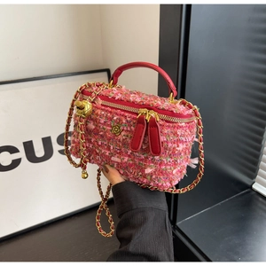 Detailed close-up of pink tweed mini vanity bag with red leather handle and gold floral charm